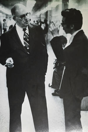 アメリカ赴任時代、タバコを手に米法曹会の仲間と談笑するほった氏の写真（本人提供）。