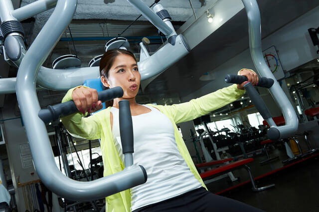 無酸素運動の筋力トレーニングを行う女性の写真。無酸素運動とは、短時間に強い力を発揮する運動。無酸素運動の種類の中で代表例は筋力トレーニングである。無酸素運動を行うことで筋量・筋力を高める効果がある。