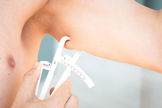キャリパー法にて二の腕の皮下脂肪厚を測定している写真。体脂肪の測定方法にはキャリパー法や生体インピーダンス法があることを示す。