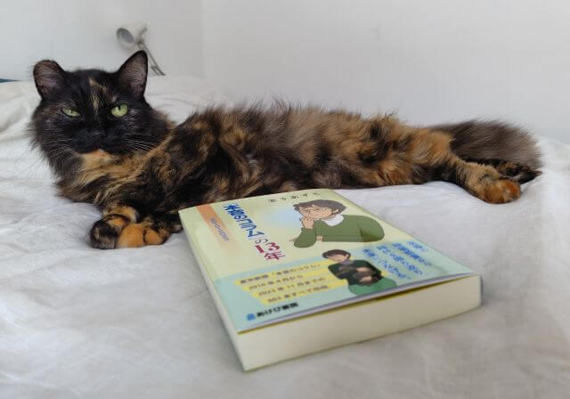 写真:著者の愛猫もふこと、その前に置かれた著書の写真