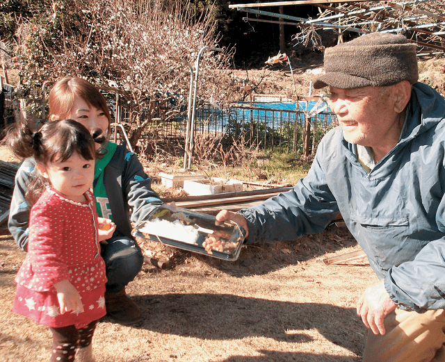 写真2:かわね来風が行う「ママ宅事業」の様子を表す写真。幼児とママさんが高齢者宅を訪れお弁当を届ける高齢者宅配サービス事業。