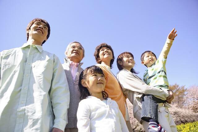 写真:青空の下にあつまる3世代家族の写真
