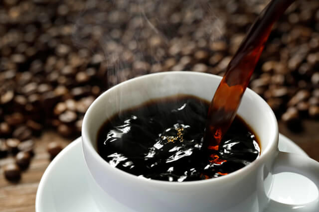 写真:コーヒーをカップに注ぐ写真。コーヒーはコーヒー豆を乾燥させて焙煎したものを粉砕し、お湯で抽出した飲み物を表す