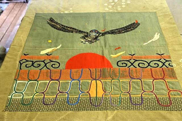 赤い目のシマフクロウが描かれた古布絵作品「浦河憧憬」（1997年）の写真。