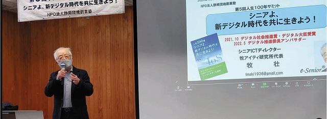 2023年1月、NPO法人静岡団塊創業塾主催の「人生100年サミット」で講演する牧さんの写真。著書『人生100歳 シニアよ、新デジタル時代を共に生きよう!』を紹介。本人提供。