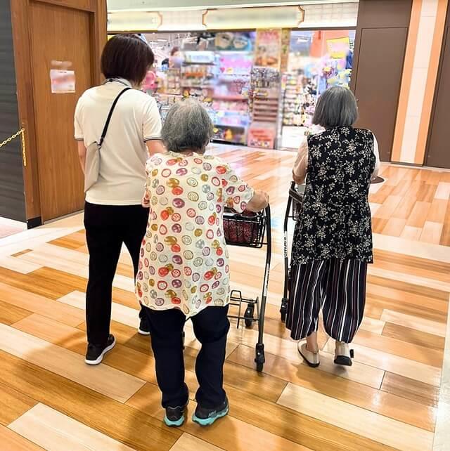 職員と利用者が共にスーパーマーケットへ移動している写真。