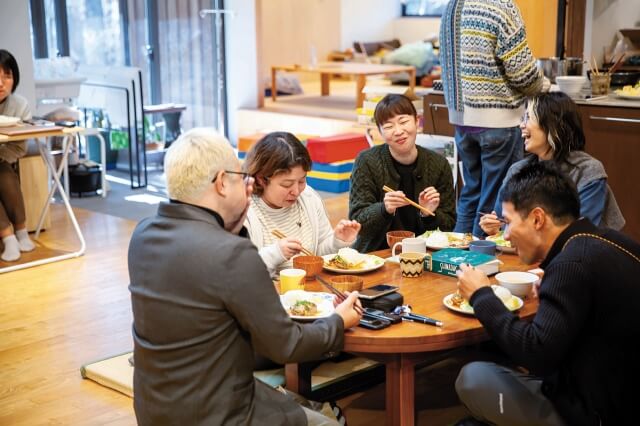 美味しい料理を囲み笑顔を見せるスタッフの皆さんの写真。