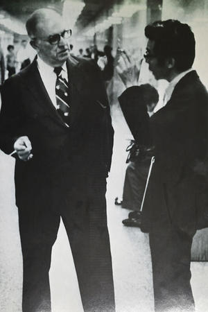 アメリカ赴任時代、タバコを手に米法曹会の仲間と談笑するほった氏の写真(本人提供)。