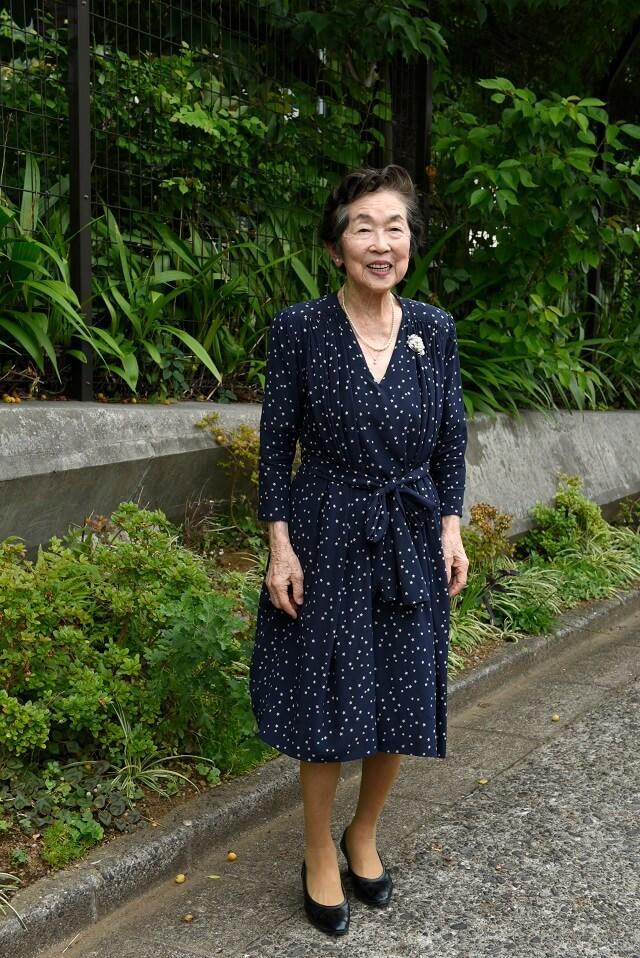 写真2：インタビュアー鮫島純子氏の写真。背筋がピンとして足取りも軽やかな様子。左胸の真珠のブローチはミキモトパールの創業者御木本幸吉氏からの贈り物。