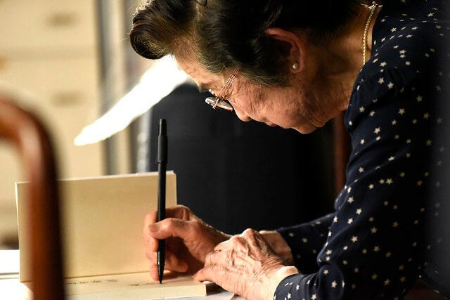 写真5：鮫島氏が毛筆ペンで一字一字ていねいに書く様子を表す写真。