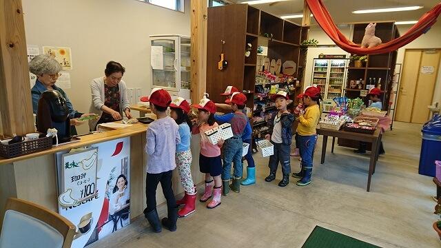 写真3：サ高住の住民で共同運営する「若松共同売店」で子供が買い物をする様子を表す写真。