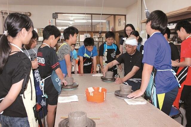 写真4：いきがいセンターで開催されている陶芸教室で、子どもたちが真剣に話を聞く様子を表す写真。
