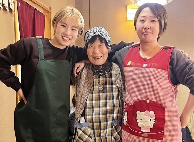 写真4、「ばあちゃんの手料理食堂」でおばあちゃんと女子大生が仲良く肩を組む写真(えんがお提供)。
