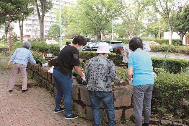 写真5：マンションの前にある歩道で地域住民が花壇の植え替えをする様子を表す写真。