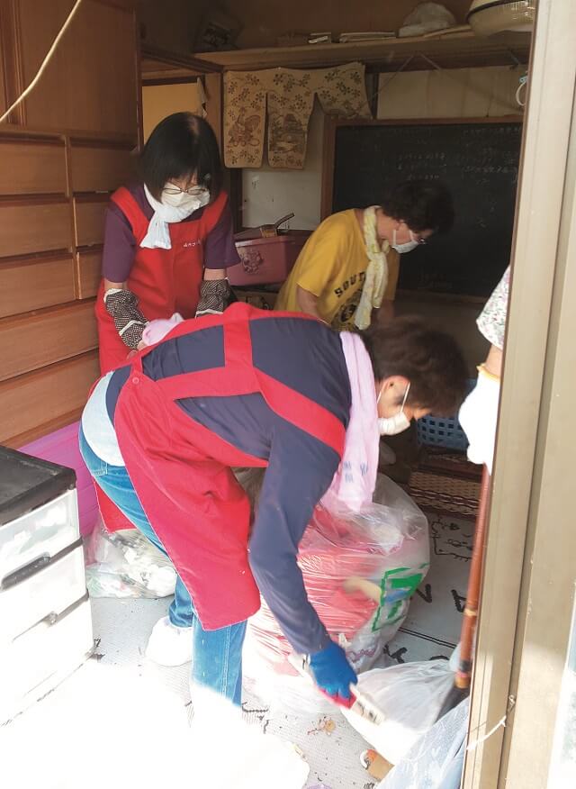 写真5:よろづや笑輪の会のメンバーがボランティア活動として片づけをする様子を表す写真。