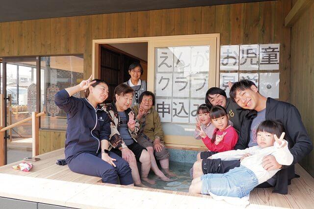 写真5、学童保育で多世代が笑顔で足湯につかる写真(えんがお提供)。