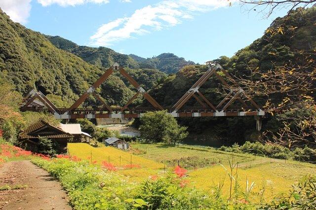 写真：日本一の木造車橋であるかりこぼうず大橋の写真。米良三山をイメージし宮崎スギの山形が3連並ぶ様子を表す。