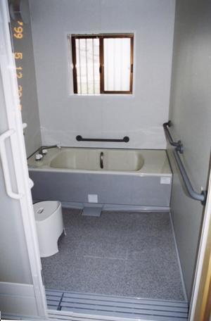 写真2：高齢者に向けて改造された浴室。浴槽の高さを低くし、跨ぎやすくしている。また、浴槽のはじに腰かけ台を設けている。また、壁には手すりを設けて、浴室内を移動しやすくしている。
