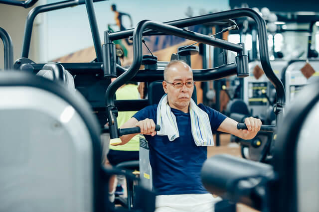 トレーニングジムで筋力トレーニングを行っている男性の写真。高齢者の健康づくりの運動を効果的にするポイントとして筋力トレーニングを取り入れることを推奨していることを示す。