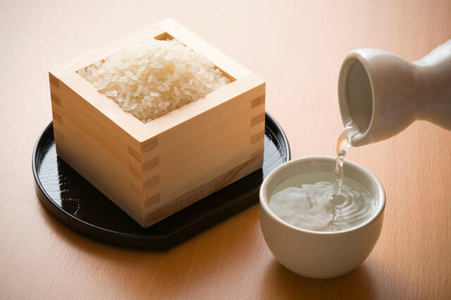 おちょこにそそがれる日本酒と一合枡に入った白米の写真。アルコールの適量として日本酒1合を示している。