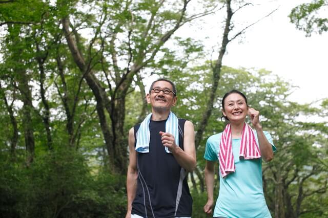 高齢者夫婦がウォーキングしている写真。健康寿命が延びるウォーキングとして大股で地面を力強く蹴って歩く、うっすらと汗ばむ程度に早歩きをする、息が弾むぐらいのペースで歩くことを表している。