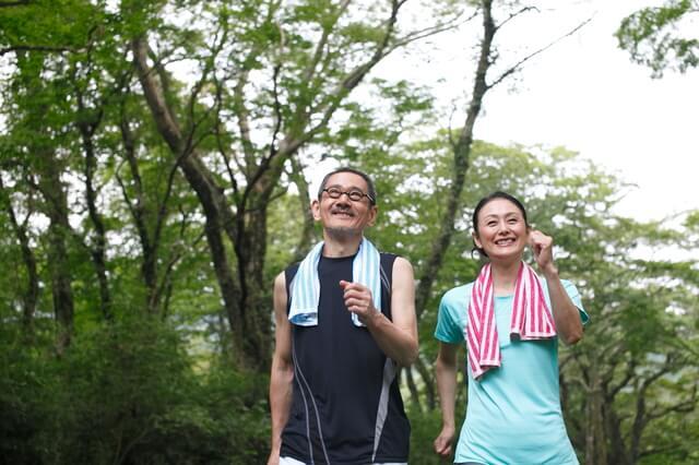 高齢者夫婦がウォーキングしている写真。健康寿命が延びるウォーキングとして大股で地面を力強く蹴って歩く、うっすらと汗ばむ程度に早歩きをする、息が弾むぐらいのペースで歩くことを表している。