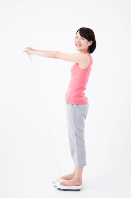 生体インピーダンス法で体脂肪を測る女性の写真。体脂肪率の測定方法には、インピーダンス法、キャリパー法、水中体重秤量法、空気置換法等がある。
