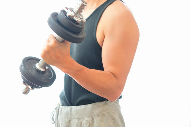 ダンベルを用い筋力トレーニングを行う男性の写真。筋力強化は健康的に、自立的に生活していくために必要不可欠な要素であることを示す。