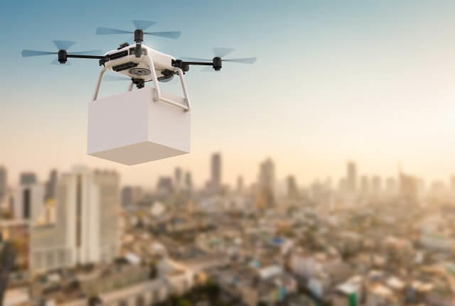 写真1:空飛ぶドローンが荷物を運んでいるイラスト