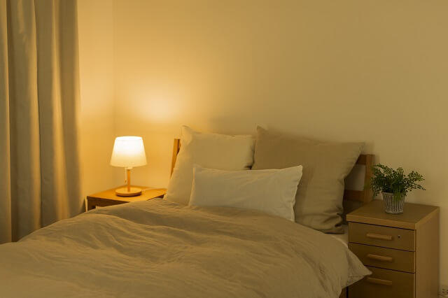 img：快眠のための環境に最適な室内の照度が暗めの寝室のベッドサイドの写真