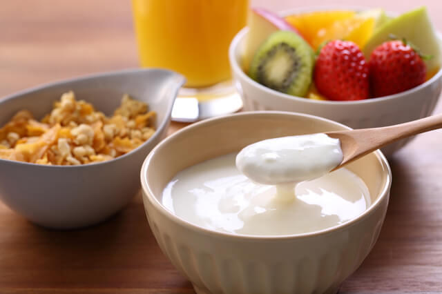 写真：フルーツとヨーグルトの写真。乳酸菌を摂り善玉菌をふやすこと、朝食をとることで腸を整える生活習慣を表している
