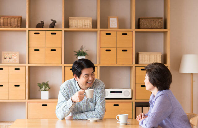 写真：夫婦が居間でコーヒーを一緒に飲んでリラックスしている雰囲気を表す写真。