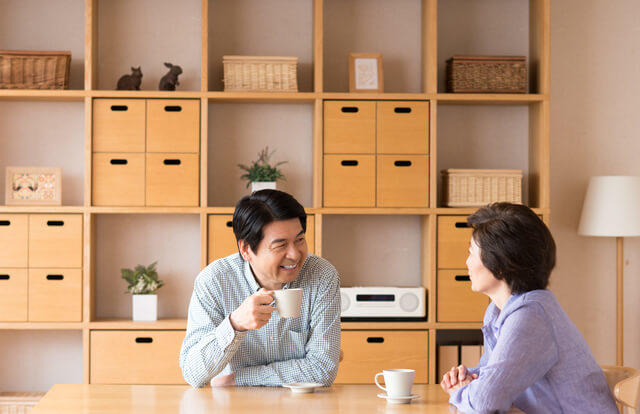 写真:夫婦が居間でコーヒーを一緒に飲んでリラックスしている雰囲気を表す写真。