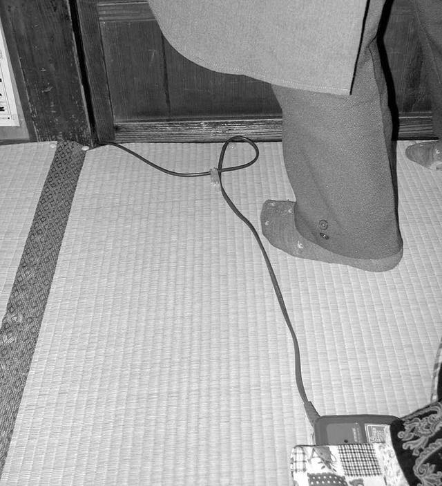 写真3：居間の電気カーペットから伸びる床を這うコンセントのコードが転倒の障害物となることを示す写真