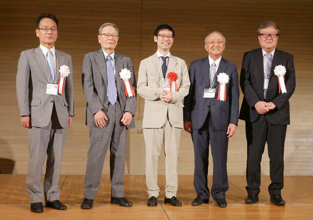 中川威氏の表彰式の様子を表す写真。