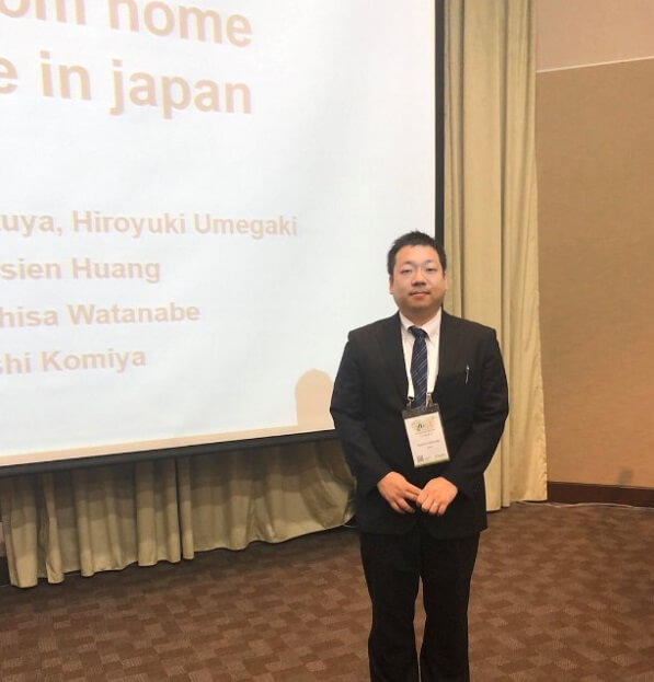 写真4:平成31年度第2期国際学会派遣事業派遣者:渡邊一久氏が発表会場の大型スクリーンの脇に立って写した写真
